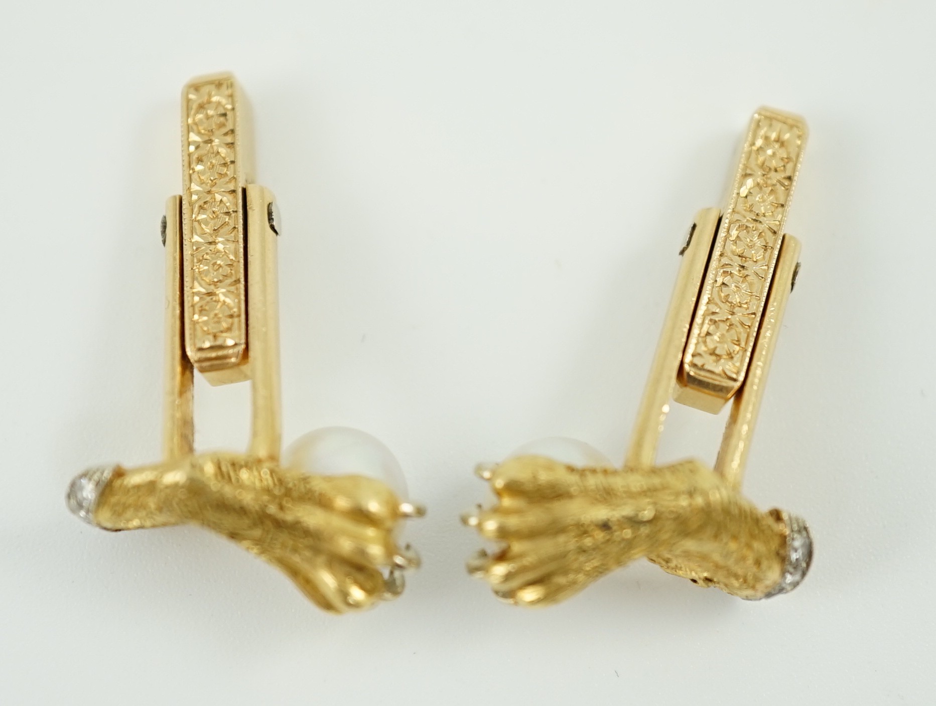 A mid 20th century pair of engraved and textured gold and platinum, diamond chip and cultured pearl cufflinks, each modelled as a lion's paw